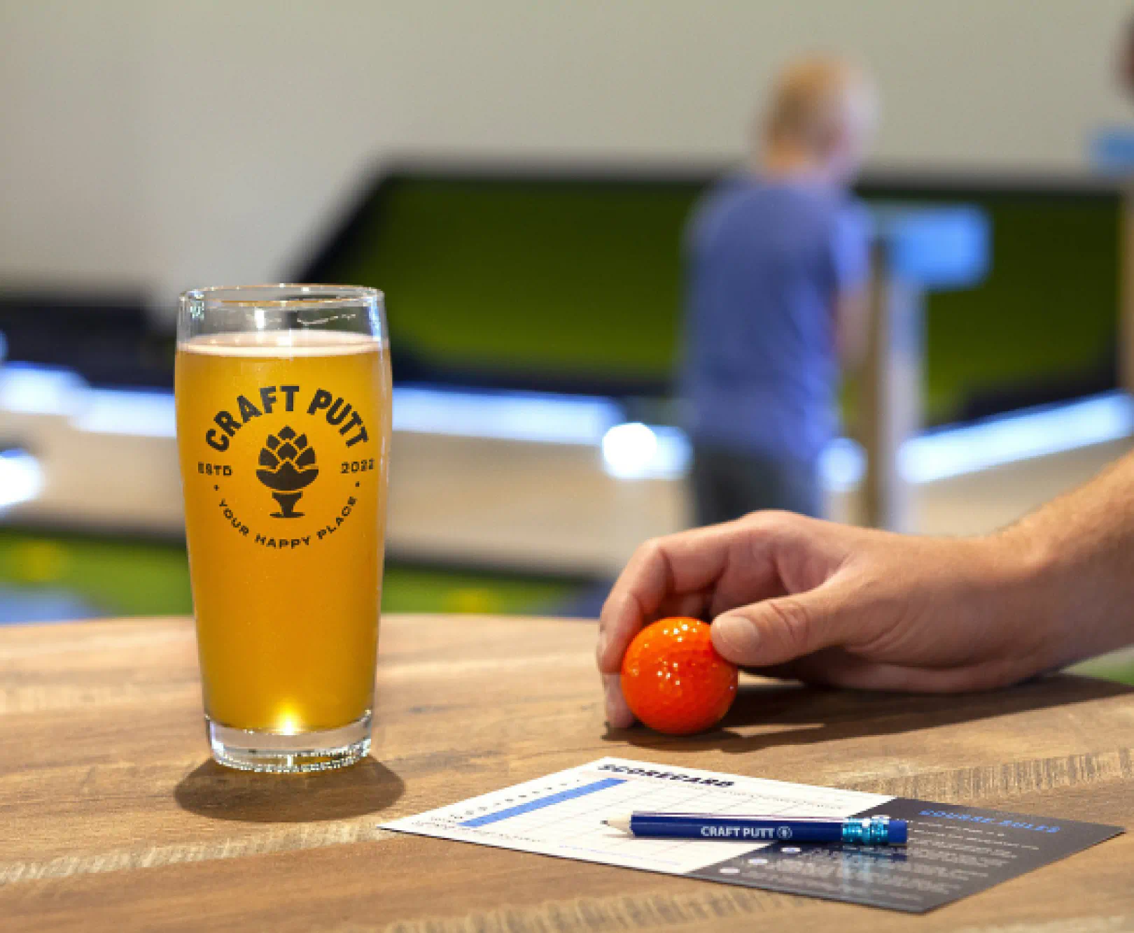 pint glass of beer with hand holding a golf ball