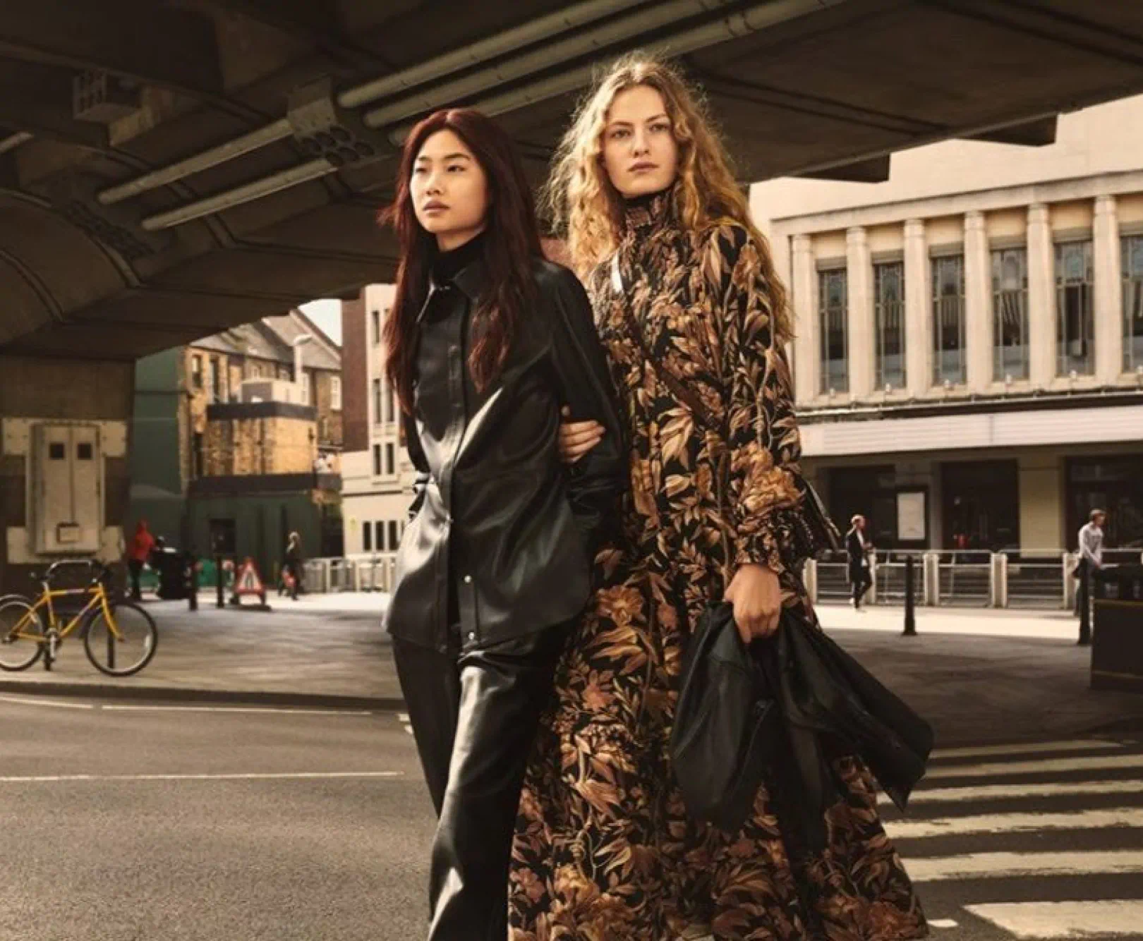 two people fashionably dressed walking across the street