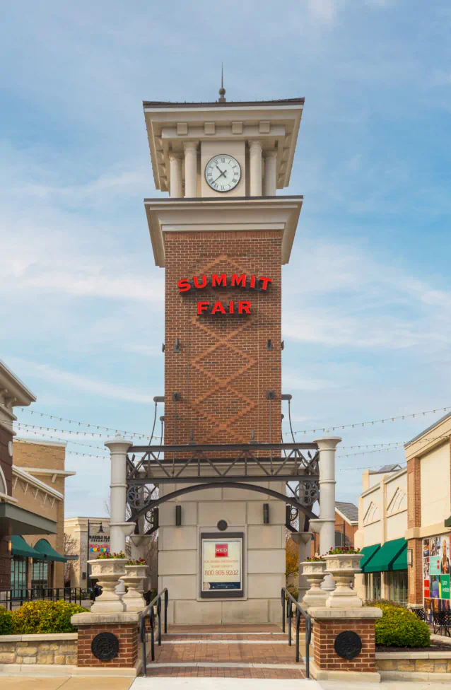 Summit Fair entrance, clock tower made of brick with the "Summit Fair" sign. Stores line either side around the clock tower.