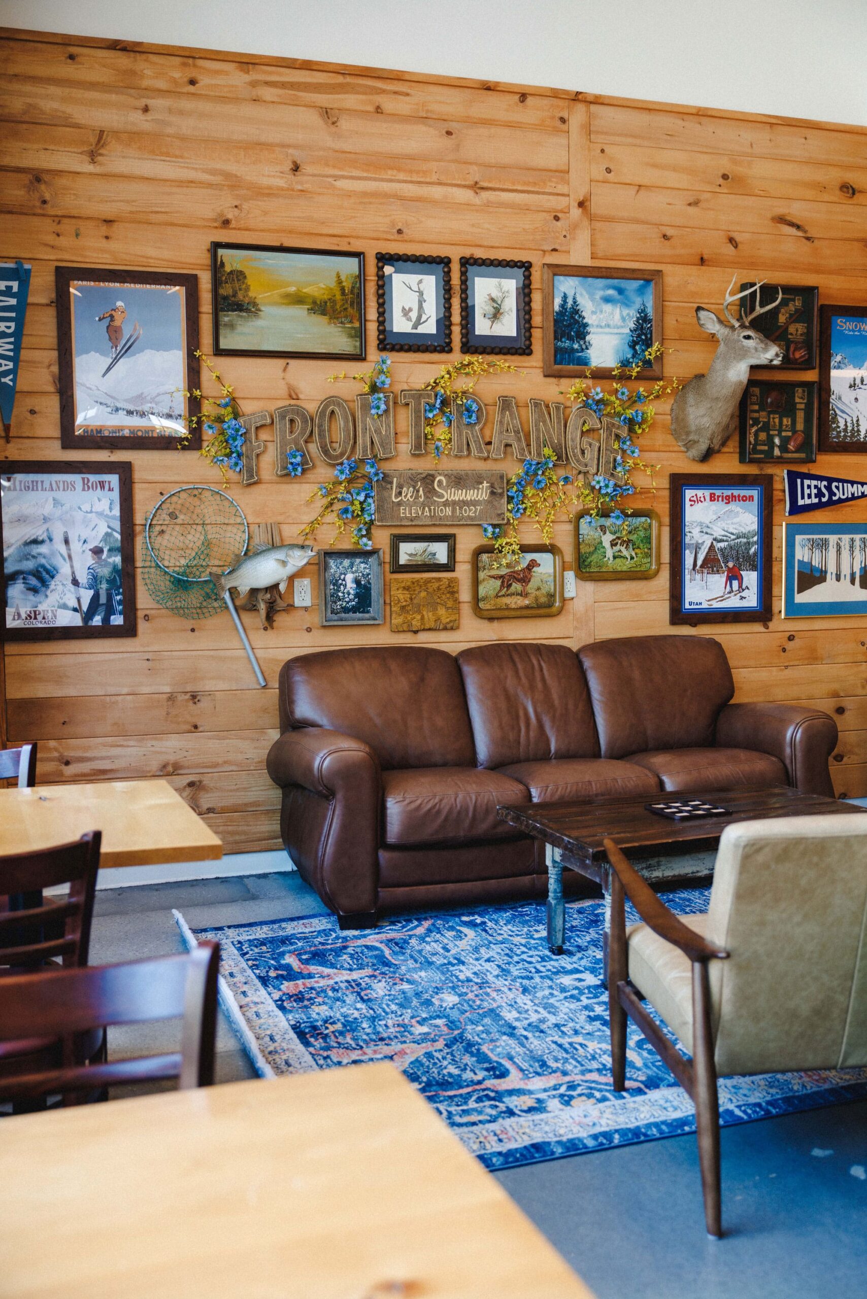 A seating area with leather couch, blue rug, frames on the wall and a sign reading "Front Range."